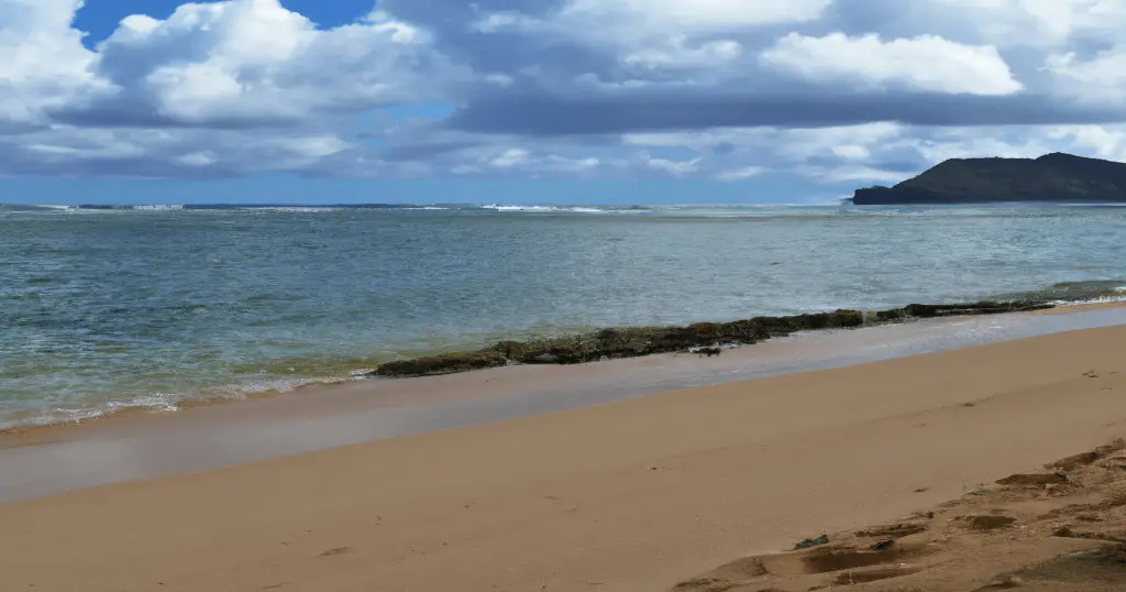 Photo of the calm shoreline of bathtub beach on Oahu, Hawaii with pretty clouds in the background