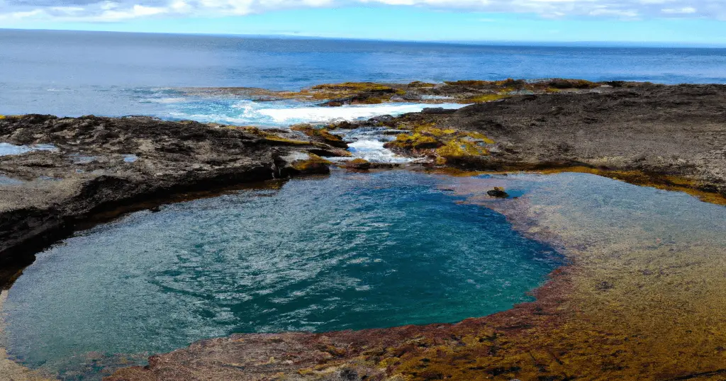 Olivine Pools during a calm day surrounded by grey lava rock partially coverd in Algae