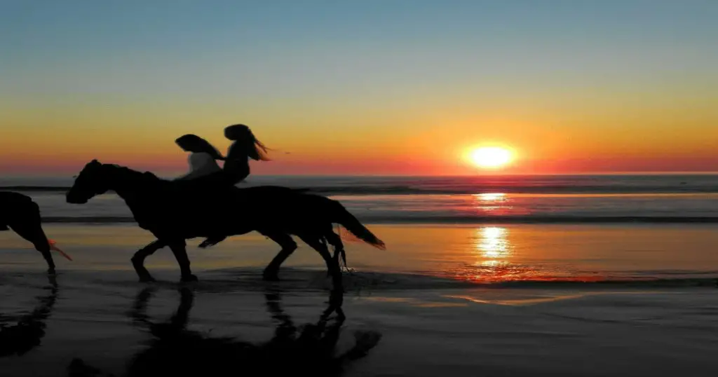2 kids riding a horse on a beach in Galveston during sunset
