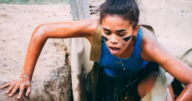 Exhausted woman scrambling through a wet mud challenge in South Africa