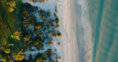 Topdown view of a white sand beach on Sanibel Island during Sunset in winter with turquoise water and dark green bushes