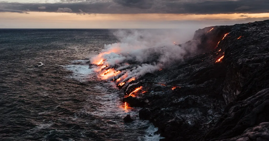 Red lava pouring into the water at the shores of the Big Island in Hawaii.
