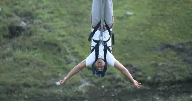 A bungee jumper with a white shirt hanging upside down.